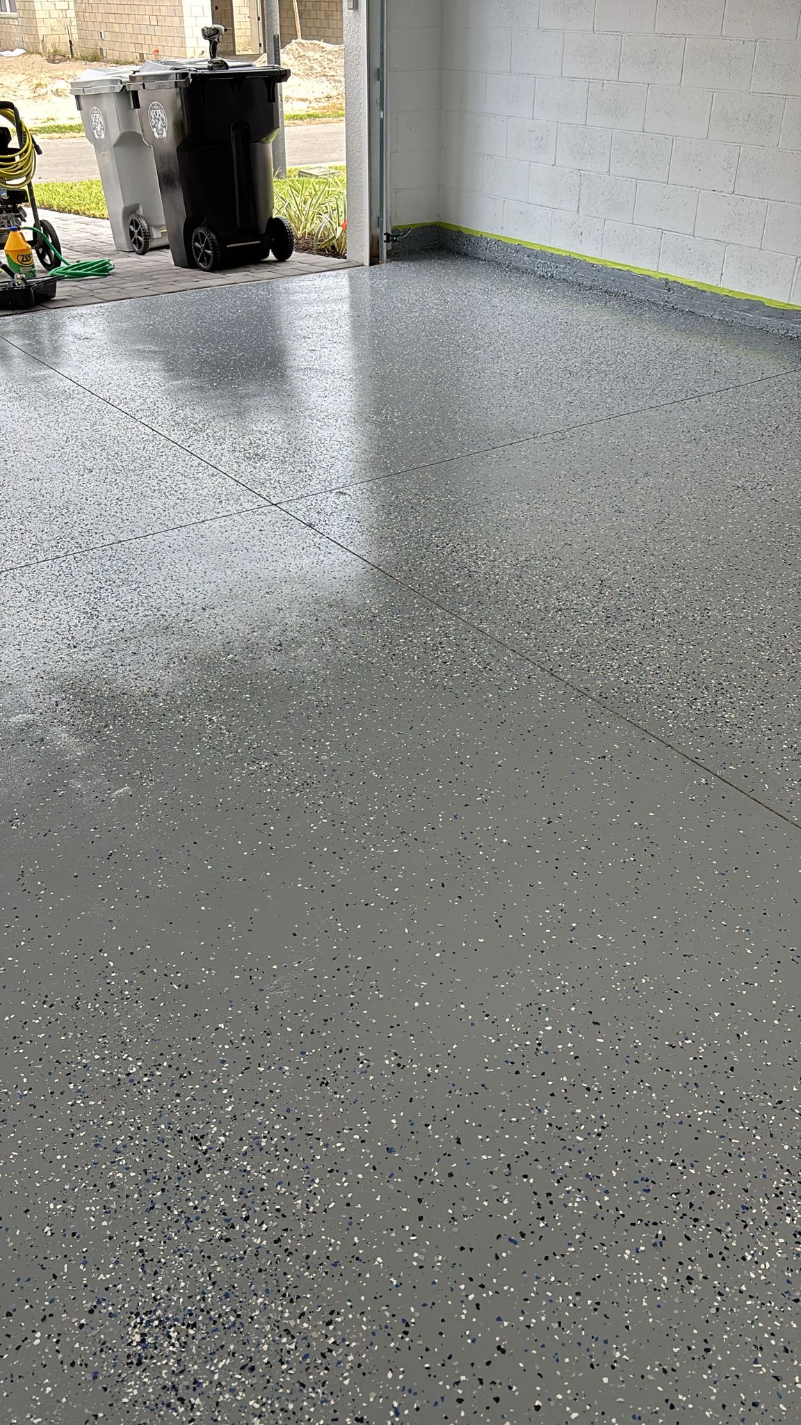 Epoxy garage floor application in progress, with wall protection